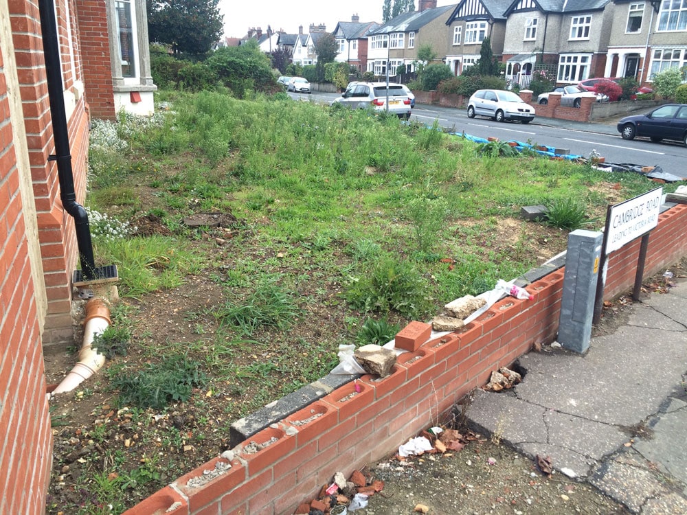 front garden with damaged wall and lots of weeds