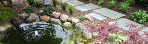 pretty circular water feature edged with pebbles and sitting beside a path made from stepping stones.