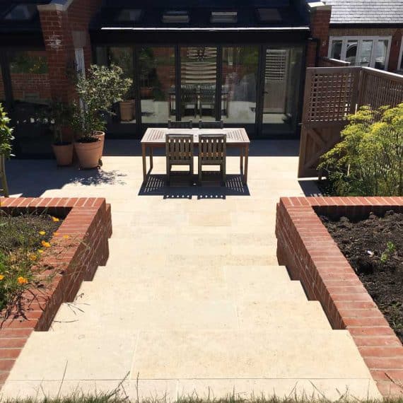 two flights of limestone outdoor steps leading down to a seating area