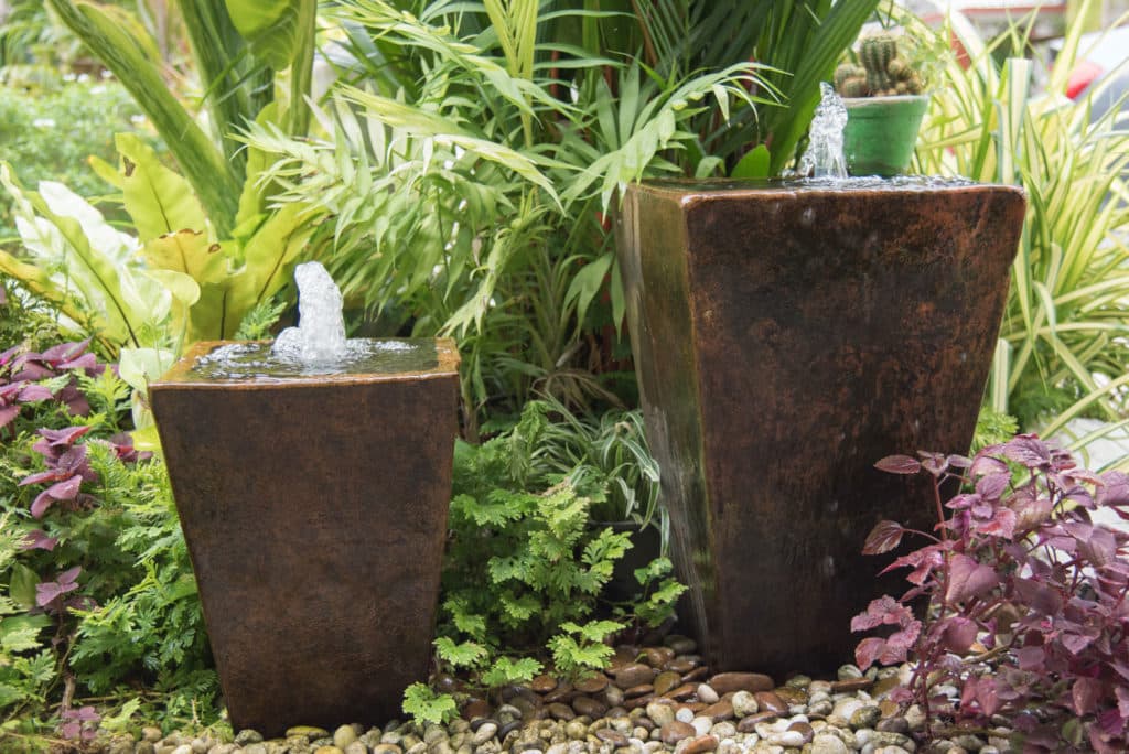 two ceramic planters converted into water features and set amongst beautiful foliage plants