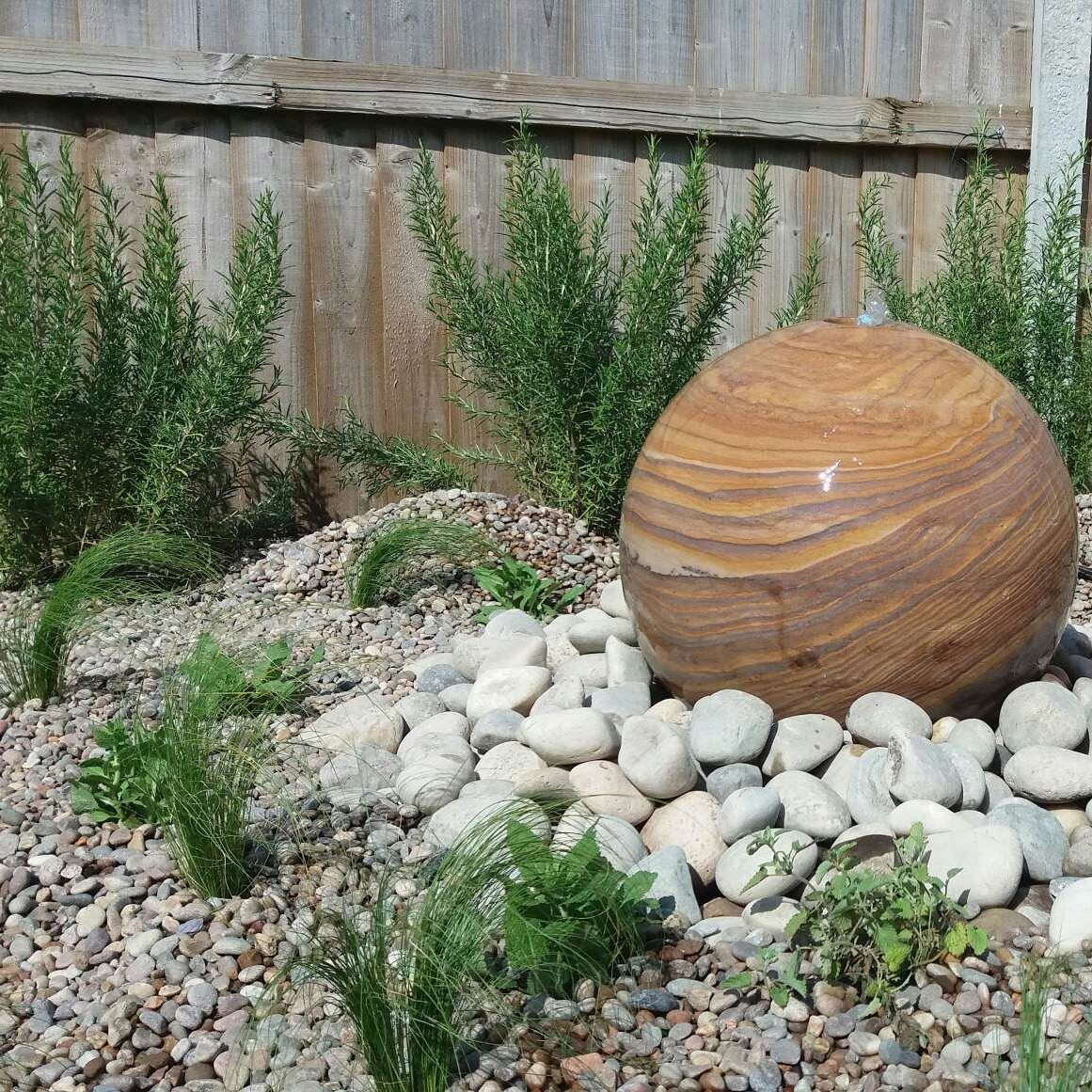 stone globe with pebbles and low maintenance planting