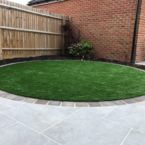 circular artificial grass lawn edged with limestone setts
