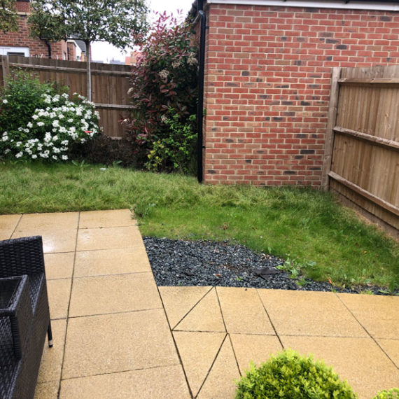 new build back garden with beige paving and worn out lawn