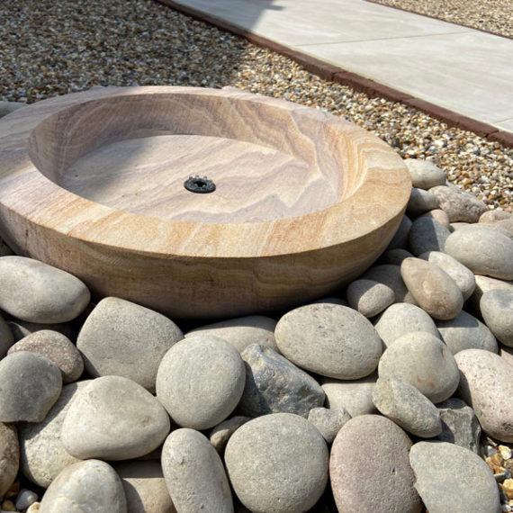 circular stone water feature surrounded by pebbles