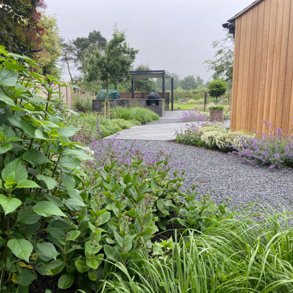garden path in grey gravel leading to porcelain patio and outdoor kitchen