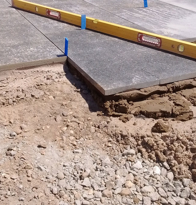 paving installation with spirit level measuring limestone pavers