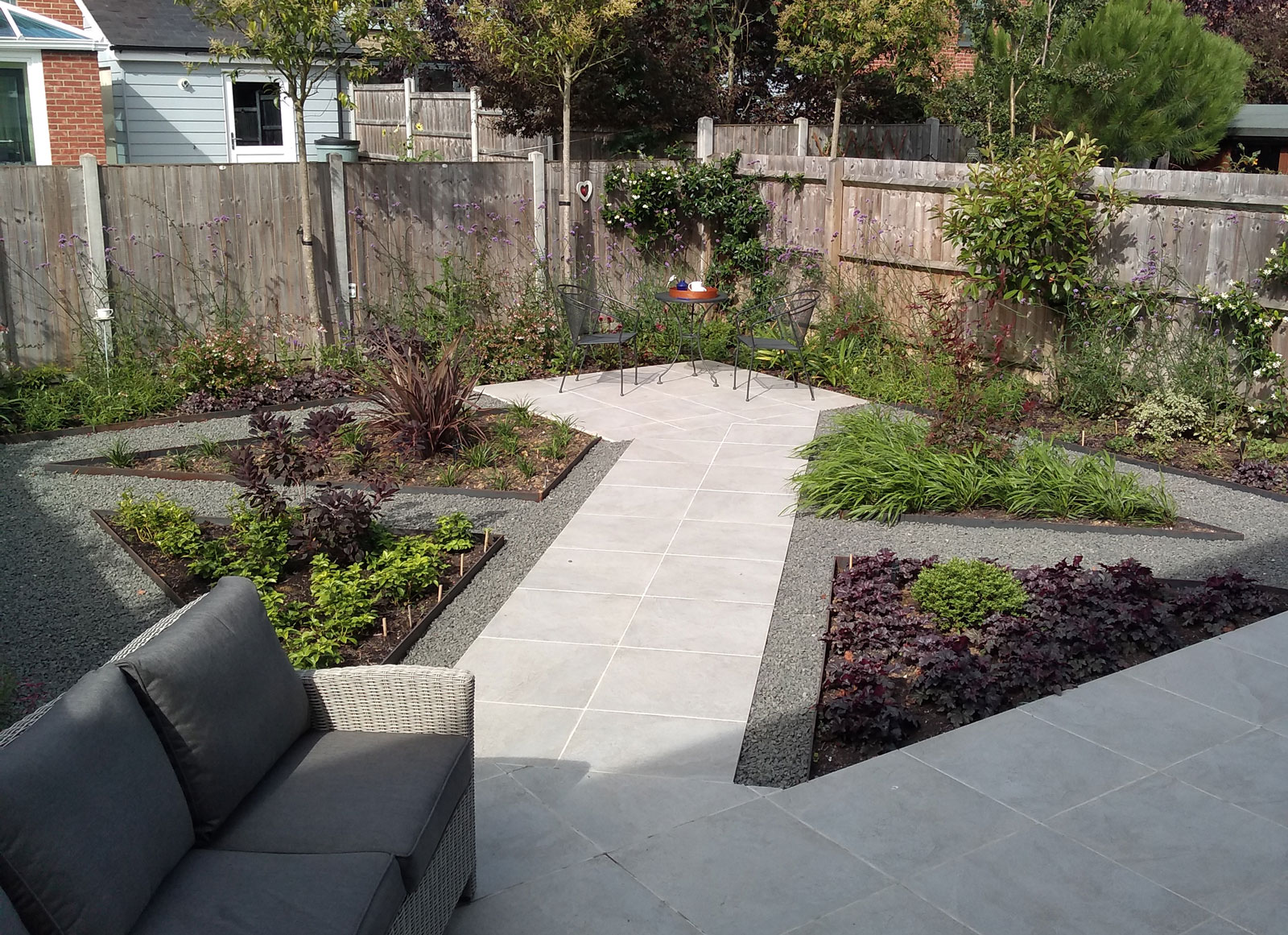 newly landscaped garden with a mix of porcelain paving and gravel paths forming a criss cross pattern with planting in between