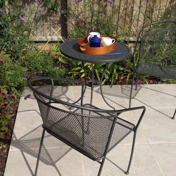 small cream coloured patio with black bistro table and two chairs
