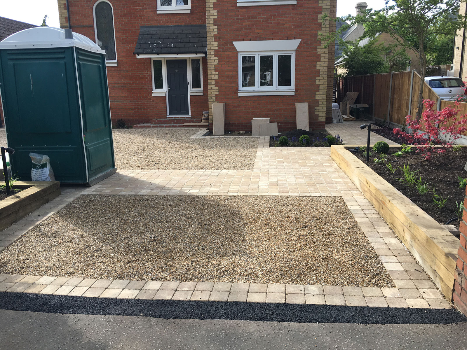 Front driveway design with gravel surfacing alternating with paved paths and decorative features