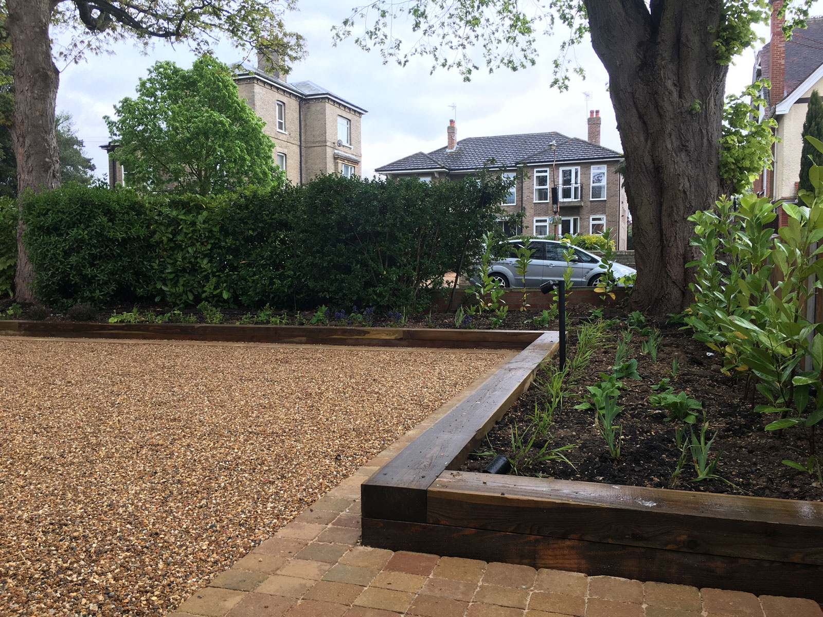 driveway design with deep timber edging and a border of sandstone pavers around gravel parking area