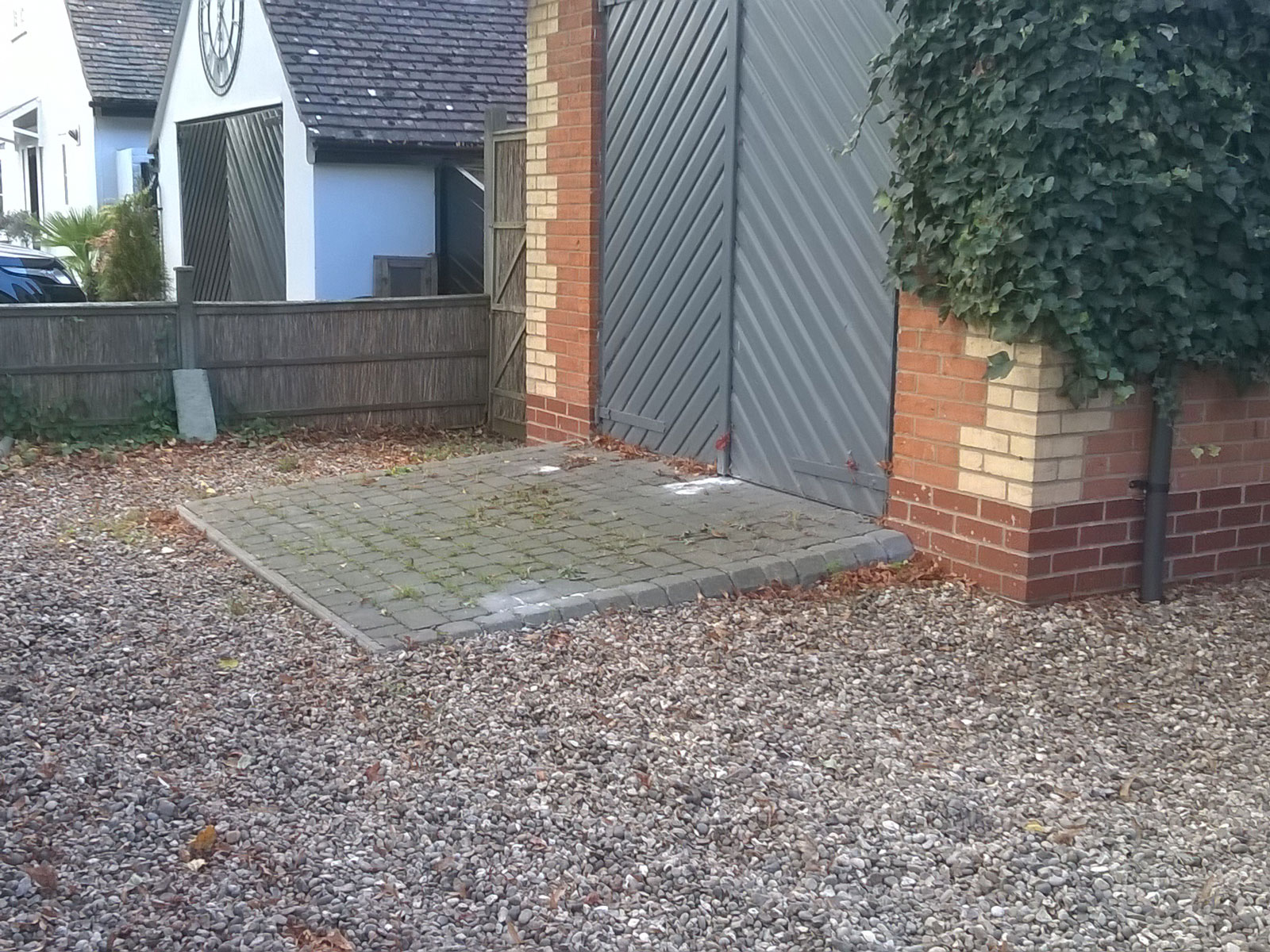domestic garage doors in grey with paved ramp to entrance surrounded by grey gravel