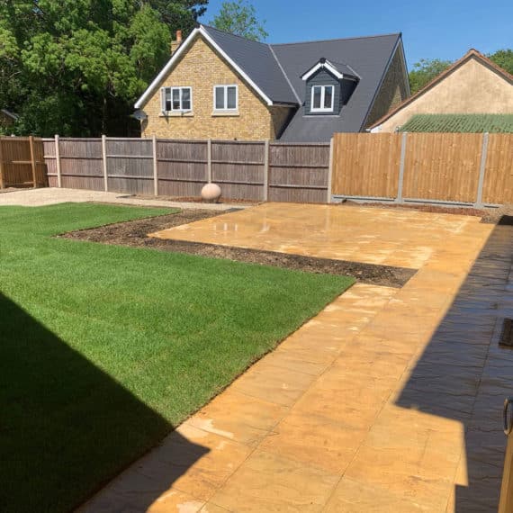 landscaped newbuild garden with buff coloured patio and turfed lawn