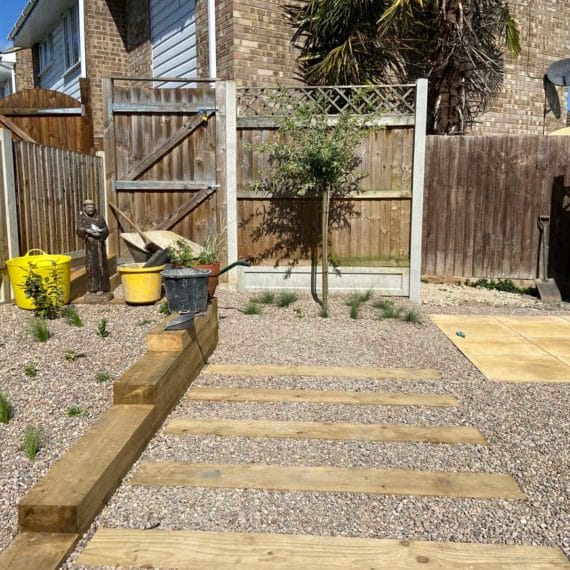 gravel mulched garden with rectangular stepping stones leading to garden gate