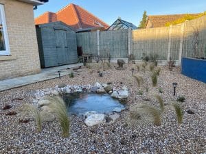 Beth Chatto inspired gravel garden with small wildlife pond surrounded by grasses and perennial plants