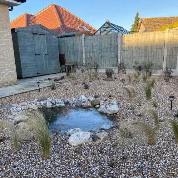 Beth Chatto inspired gravel garden with small wildlife pond surrounded by grasses and perennial plants