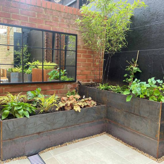 planted rectangular containers and a large wall mirror adding interest to a small paved garden
