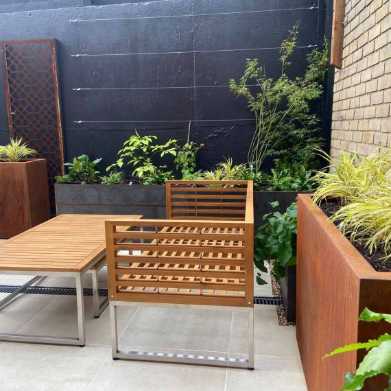 Timber and chrome garden furniture in a paved garden