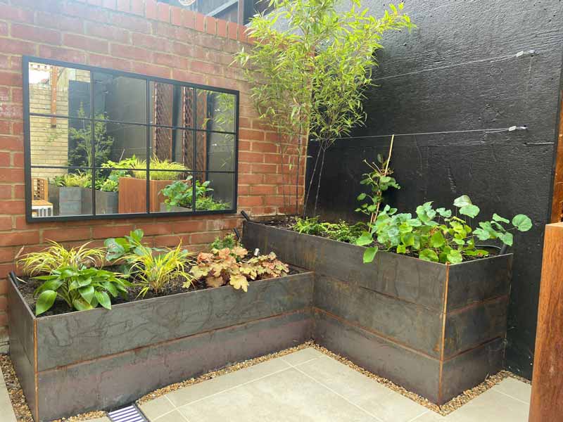 back garden ideas for small gardens include using mirrors to make the space feel larger