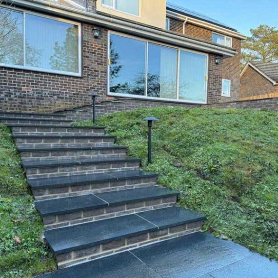 1970's property with steps approaching it from the bottom of a steeply sloping bank of wildflower matting
