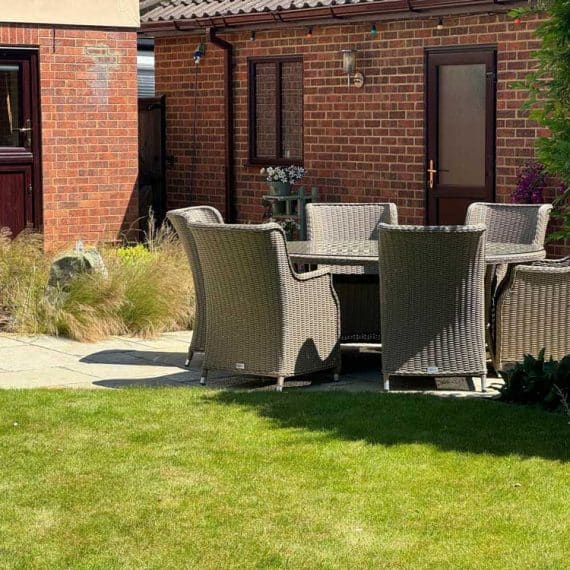 rattan outdoor dining set on large patio adjacent to lawns